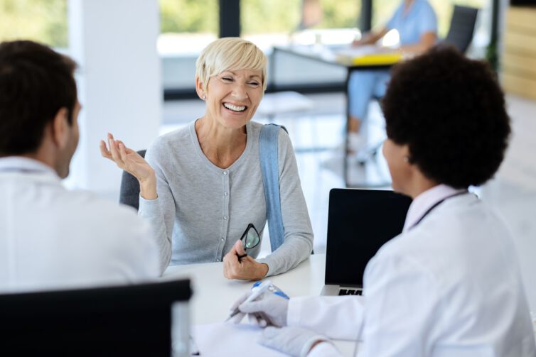 Happy mature woman talking to her doctor at medical clinic.